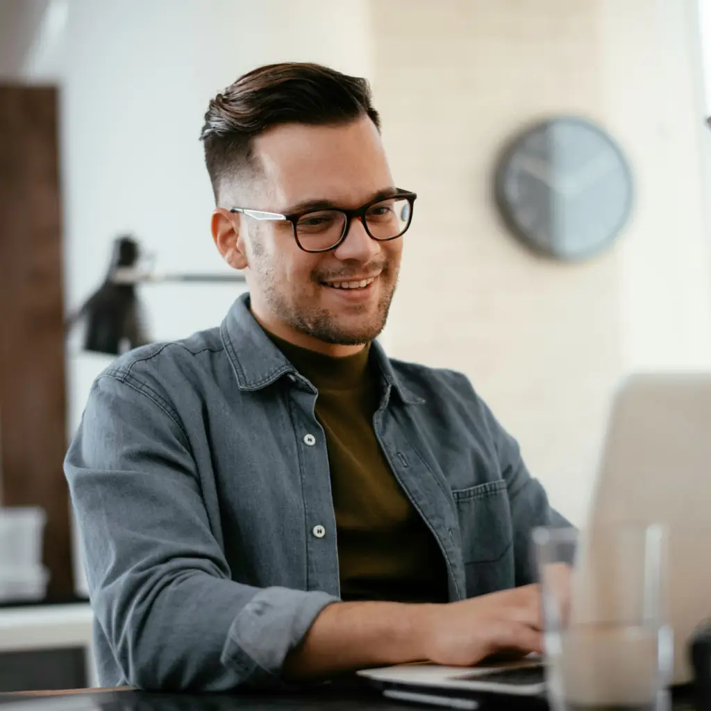 A young man in glasses working on a computer.