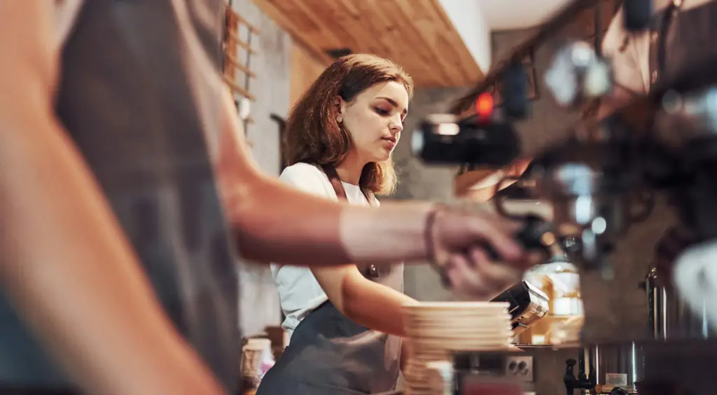 A young woman working as a barista in a coffee shop.